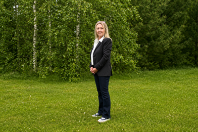 Elle Cass standing in a garden in a black suit