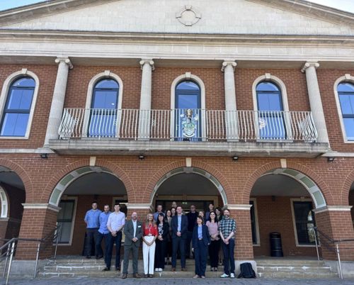 A group of people standing on steps outside a neo classical building