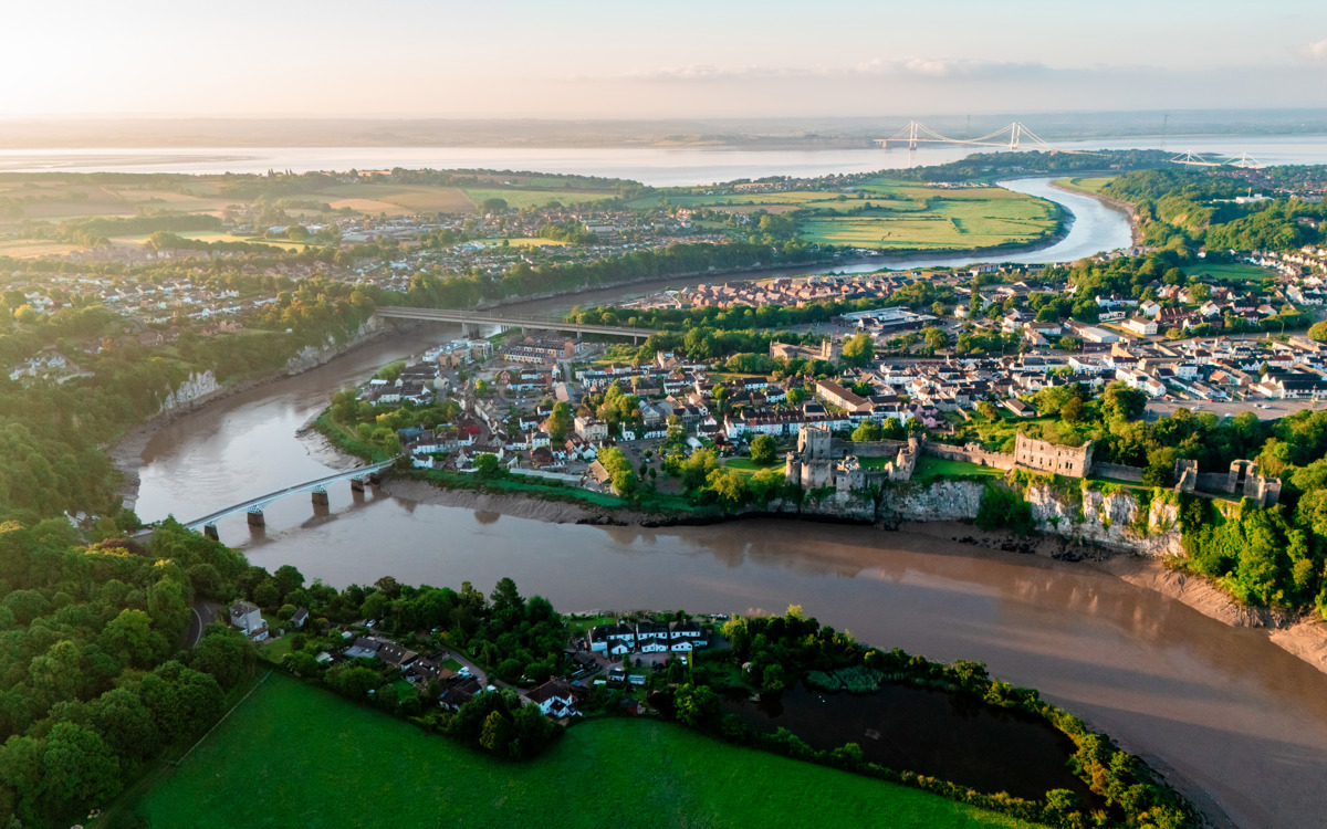 Drone photo of Chepstow including the river, houses, the Prince of Wales Bridge and the Severn Estuary.